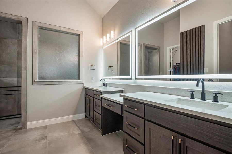 Bathroom with tile patterned flooring, double vanity, and vaulted ceiling