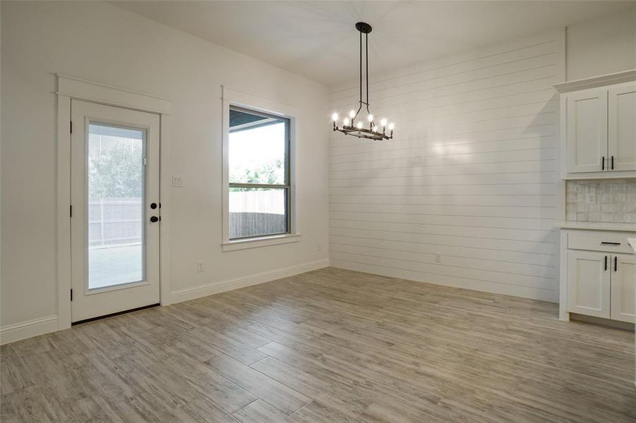 Unfurnished dining area with a chandelier and light wood-type flooring