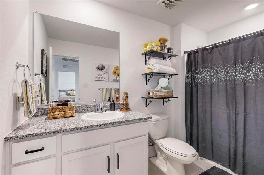 Bathroom with a shower with shower curtain, vanity, toilet, and tile patterned floors