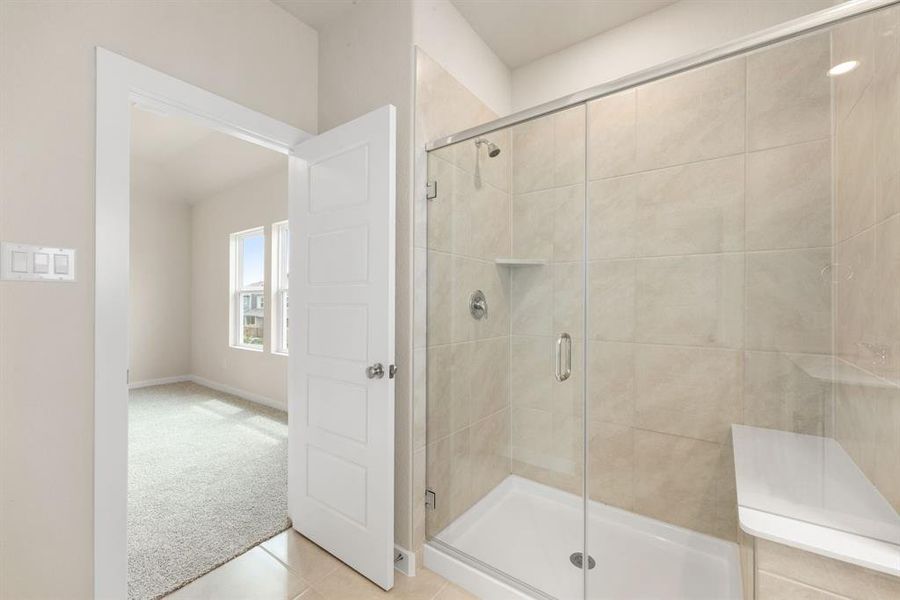 This additional view of the primary bath showcases an oversized walk-in shower with tile surround and a seating, perfect for soaking after a long day.