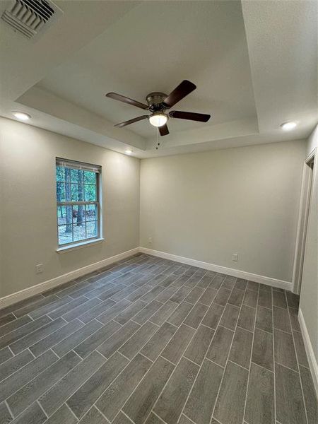 Empty room featuring a tray ceiling, dark hardwood / wood-style flooring, and ceiling fan