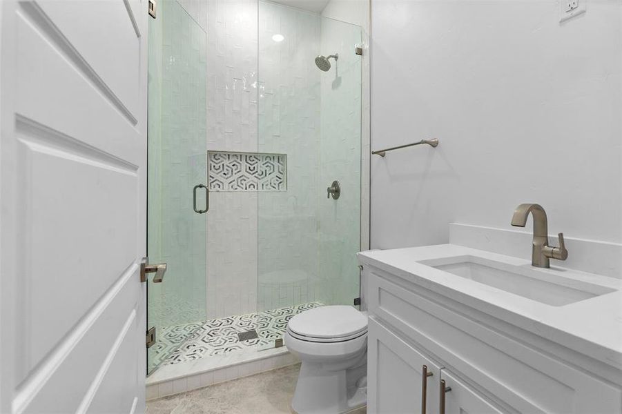 Bathroom with vanity, tile patterned floors, toilet, and a shower with door