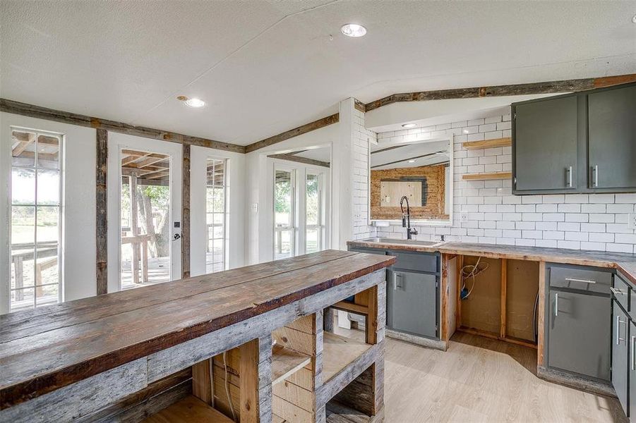 Kitchen with light wood-type flooring, a healthy amount of sunlight, backsplash, and butcher block countertops