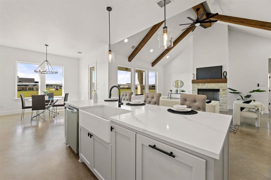 Kitchen featuring a wealth of natural light, hanging light fixtures, a fireplace, and a center island with sink