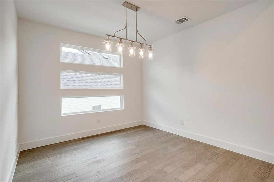 Spare room with a notable chandelier and light hardwood / wood-style flooring