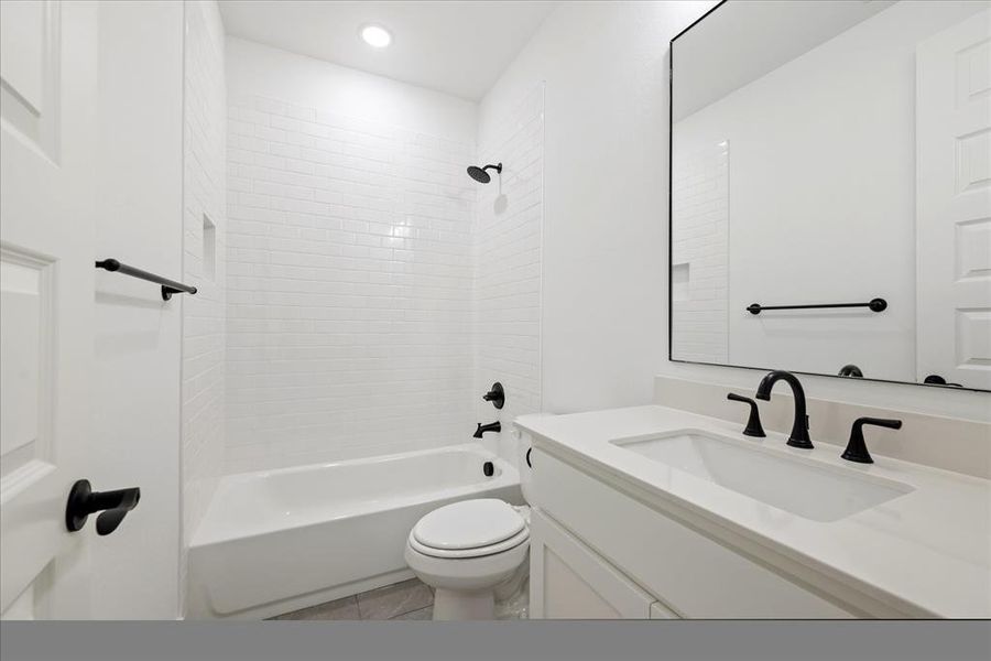 Full bathroom featuring vanity, tiled shower / bath, tile patterned flooring, and toilet