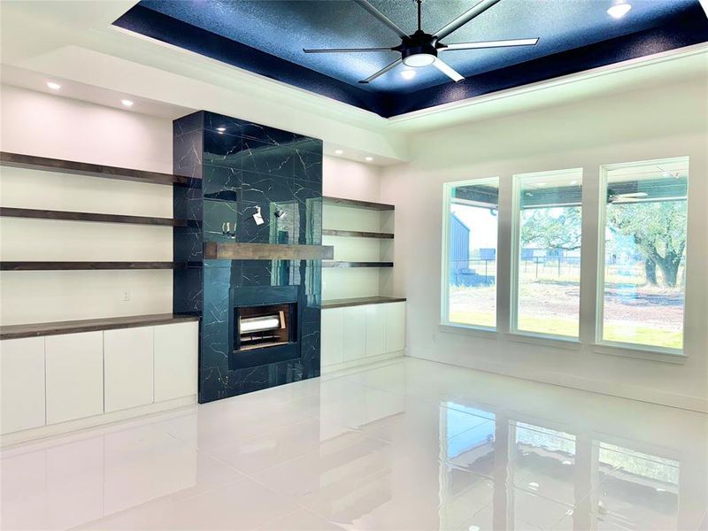 Unfurnished living room featuring ceiling fan, tile patterned floors, and a raised ceiling