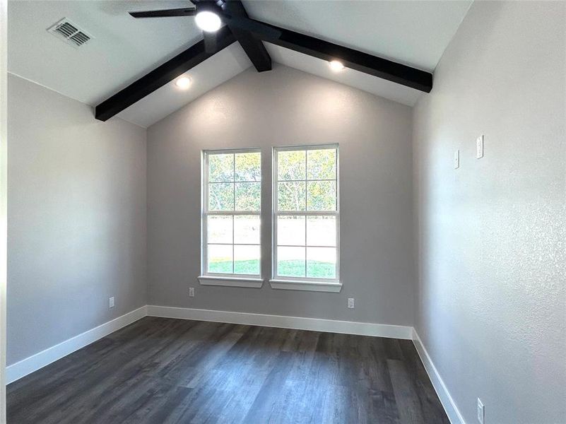 Spare room featuring dark wood-type flooring, lofted ceiling with beams, and ceiling fan