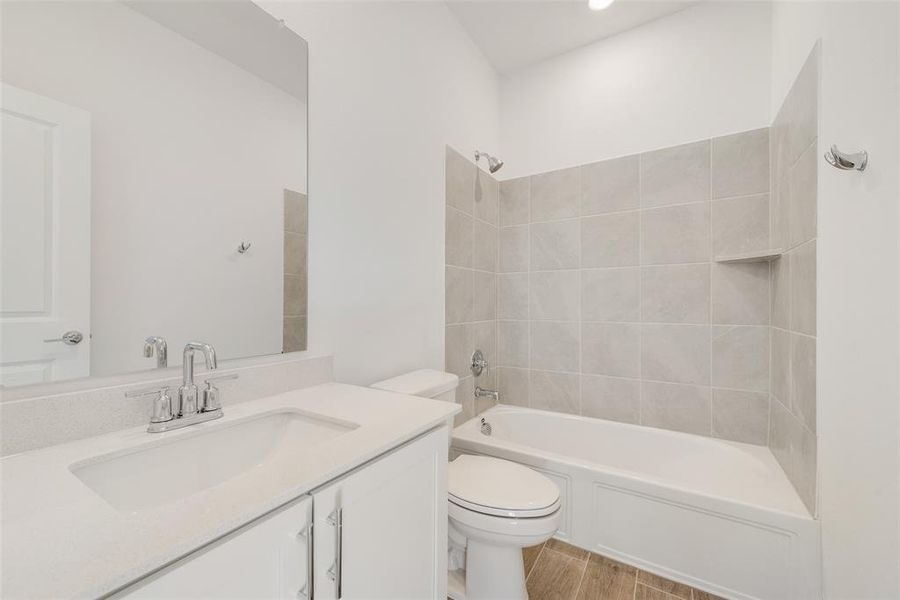 Full bathroom featuring toilet, tiled shower / bath combo, vanity, and hardwood / wood-style floors