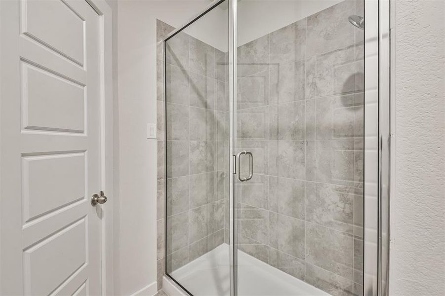 This is a modern bathroom featuring a glass-enclosed shower with gray tiled walls, offering a clean and contemporary look.
