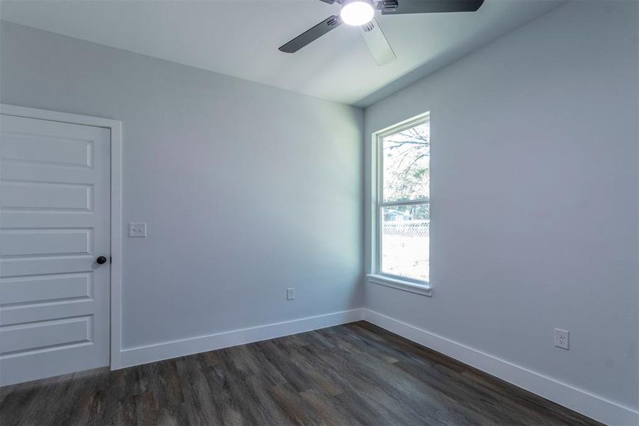 Empty room featuring ceiling fan and dark hardwood / wood-style floors