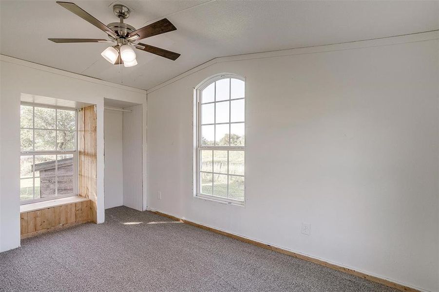 Unfurnished bedroom featuring ceiling fan, carpet floors, and vaulted ceiling