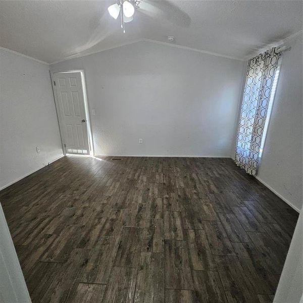 Spare room featuring dark wood-type flooring, lofted ceiling, and ceiling fan