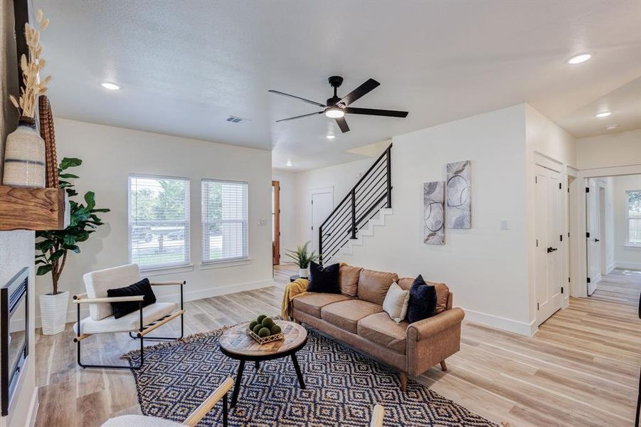 Living room with ceiling fan, light hardwood / wood-style floors, and a tile fireplace