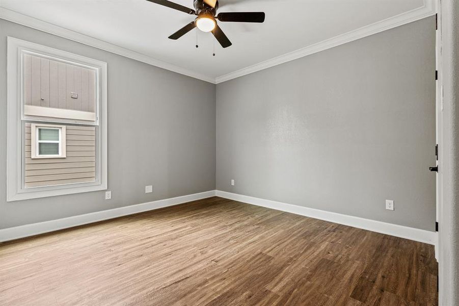 Bedroom with ceiling fan, hardwood / wood-style flooring, and crown molding
