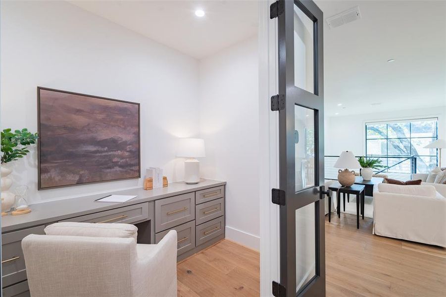 Office area with built in desk and light hardwood flooring