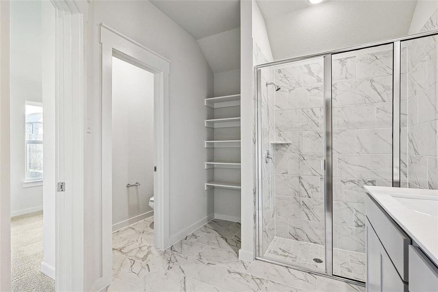 Bathroom featuring toilet, tile patterned flooring, vanity, lofted ceiling, and a shower with shower door