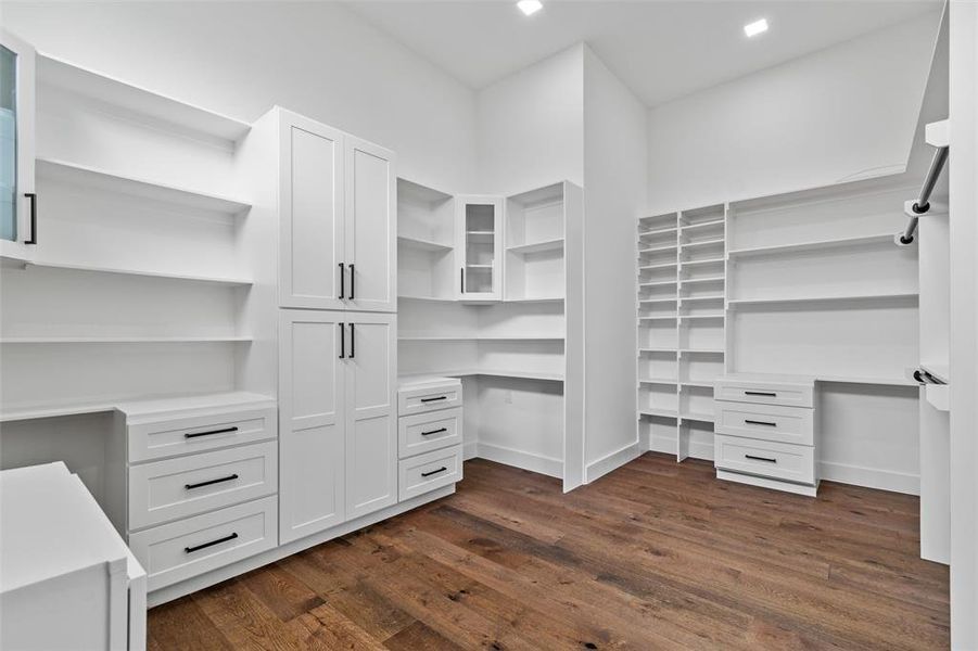Spacious closet featuring dark hardwood / wood-style floors and built in desk