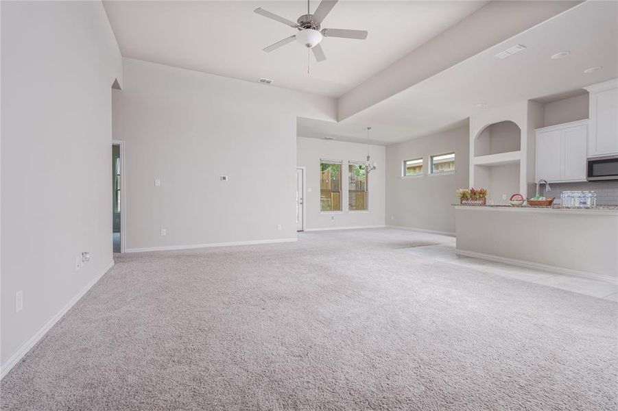 Unfurnished living room featuring light colored carpet and ceiling fan