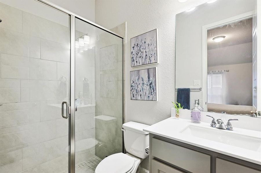 Bathroom with vanity, toilet, and a shower with shower door