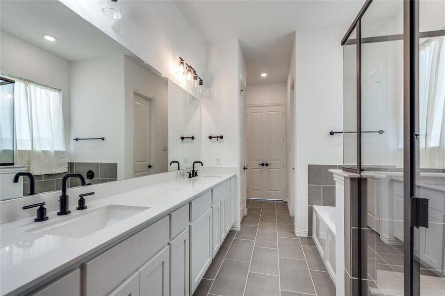 Bathroom featuring tile patterned flooring, a bath, and vanity