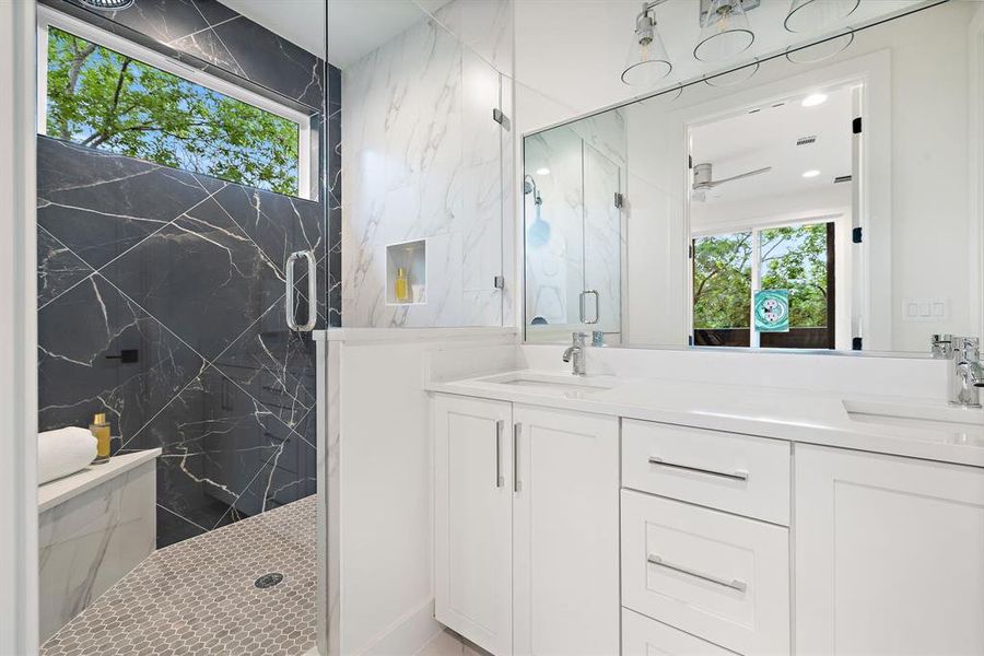 Primary bathroom with gorgeous frameless walk-in shower with bench and window that brings in natural light. Double vanity with Quartz countertops.