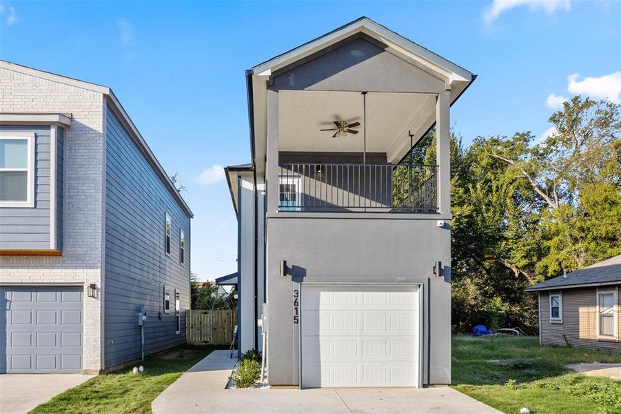 View of home's exterior featuring a balcony, a garage, a yard, and ceiling fan