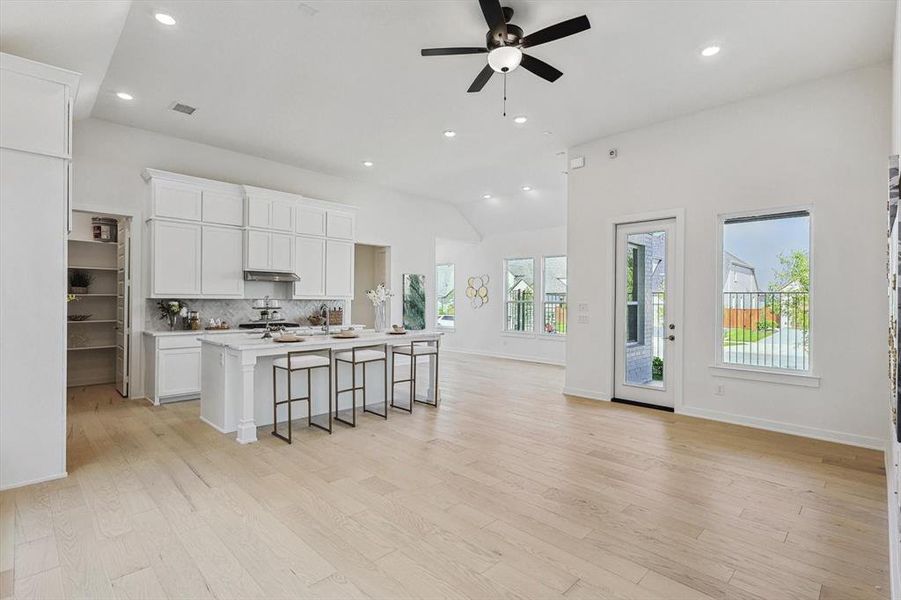 Kitchen featuring ceiling fan, light hardwood / wood-style flooring, a kitchen island with sink, and tasteful backsplash