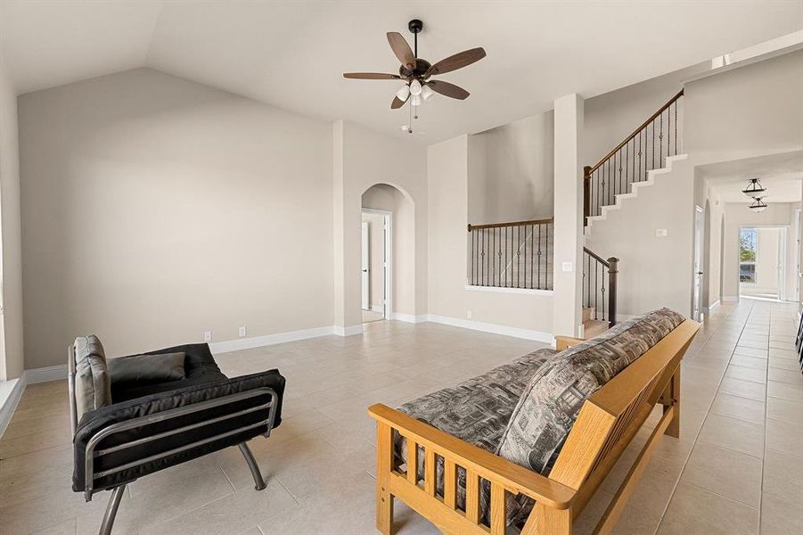 Tiled living room with ceiling fan and vaulted ceiling