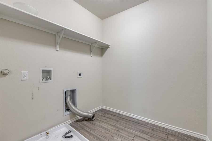 Clothes washing area featuring wood-type flooring, hookup for a gas dryer, washer hookup, and electric dryer hookup