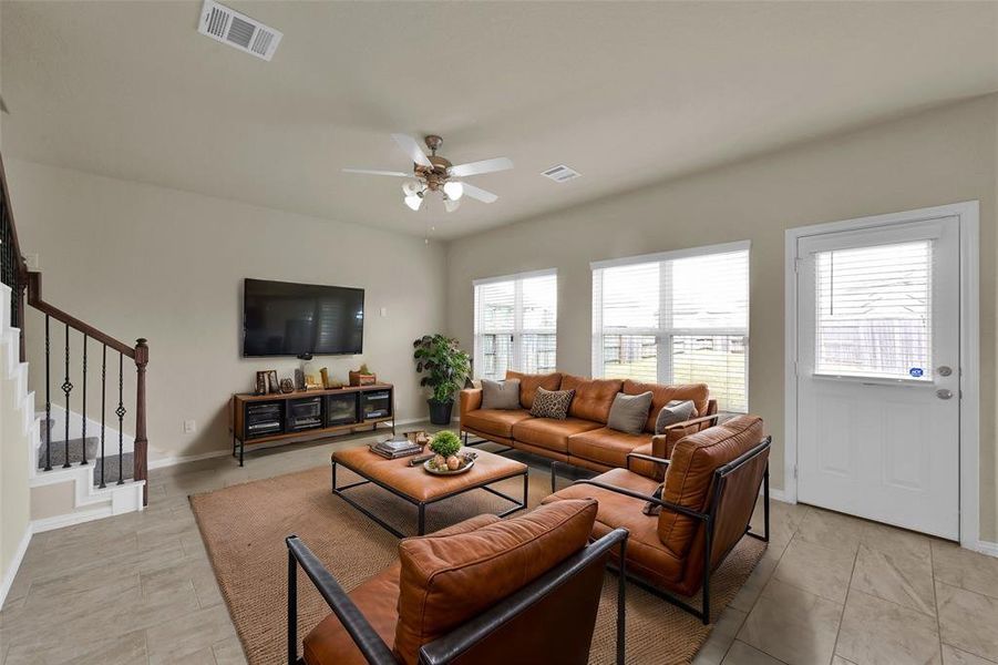 (Virtually staged)This is a spacious living room with natural light, featuring a modern staircase, tile flooring, and plenty of entertainment space. Ideal for relaxation and entertainment.