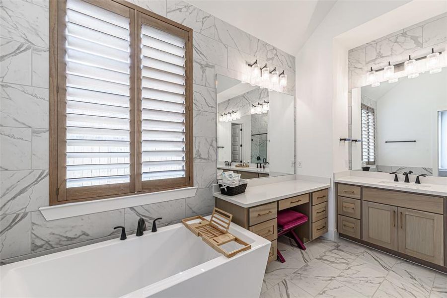 Dazzling tiled walls, custom plantation shutters and a vanity area are among the luxury features of the primary bathroom.