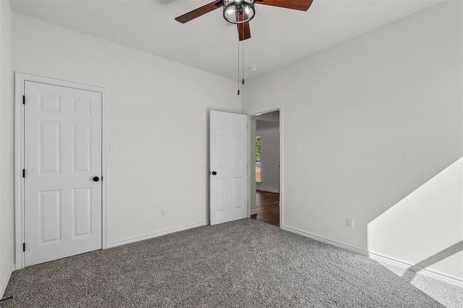 Unfurnished bedroom featuring dark carpet and ceiling fan