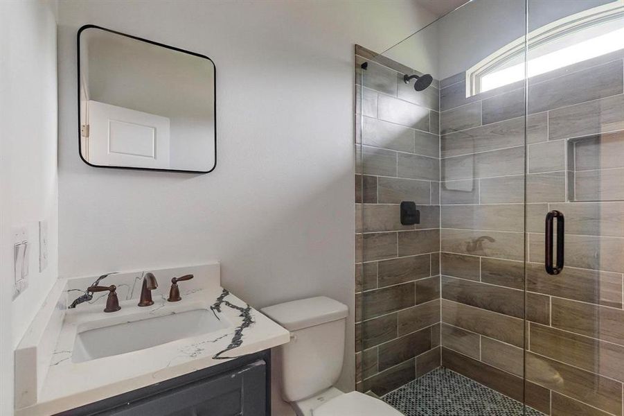 Bathroom featuring vanity, toilet, and an enclosed shower