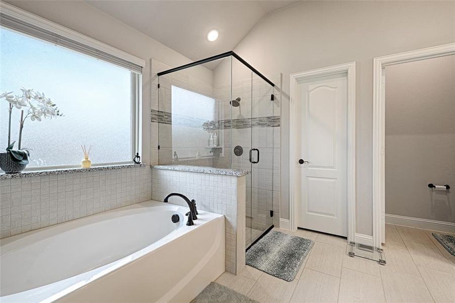 Bathroom with a healthy amount of sunlight, tile patterned floors, separate shower and tub, and vaulted ceiling