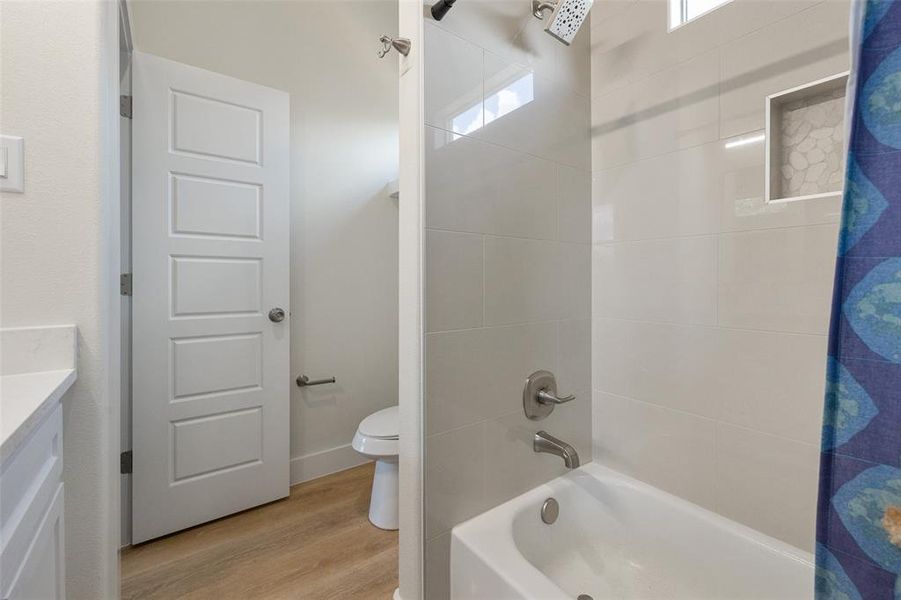 Full bathroom featuring shower / tub combo, vanity, toilet, and luxury vinyl floors