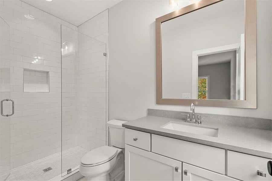 Bathroom with an enclosed shower, toilet, and vanity with extensive cabinet space