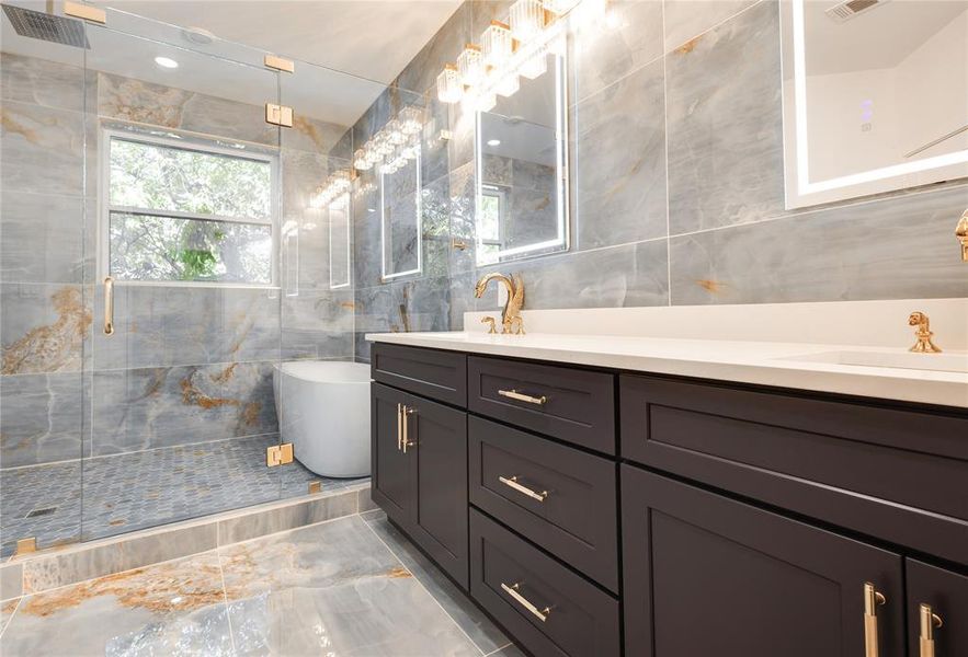 Bathroom featuring tile floors, an enclosed shower, double sink vanity, and tile walls