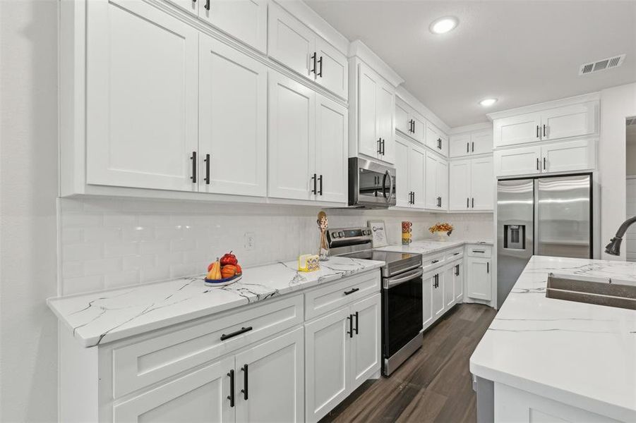 Kitchen featuring stainless steel appliances, white cabinetry, sink, dark hardwood / wood-style floors, and decorative backsplash