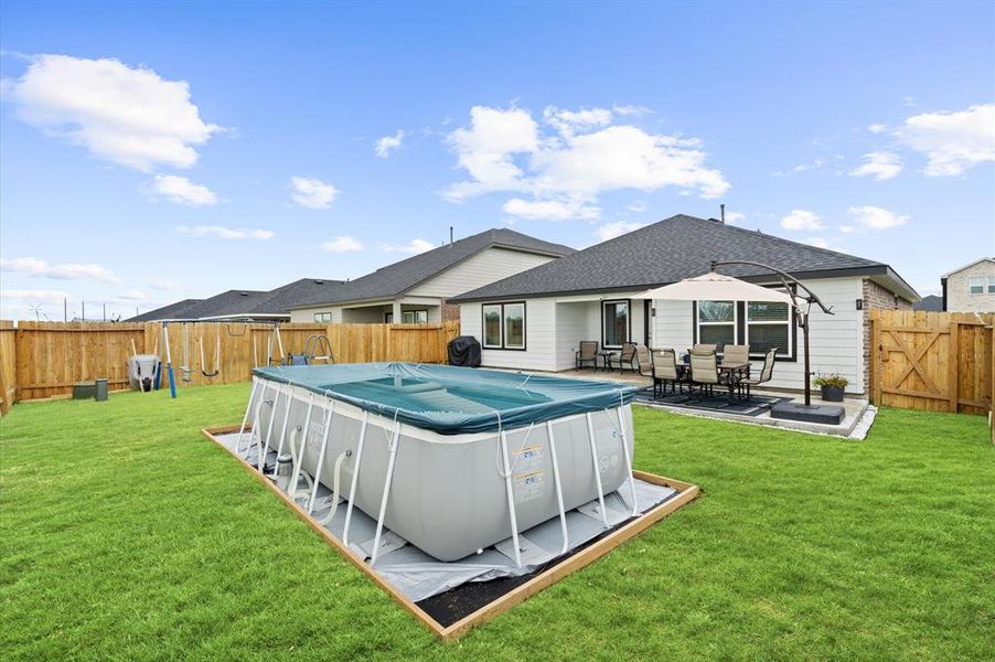 This is a spacious backyard featuring a large above-ground pool ideal for outdoor entertainment and relaxation. The yard is enclosed by a tall, wooden privacy fence.