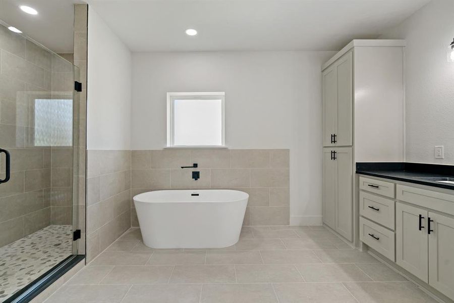 Bathroom with tile walls, shower with separate bathtub, tile patterned floors, and vanity