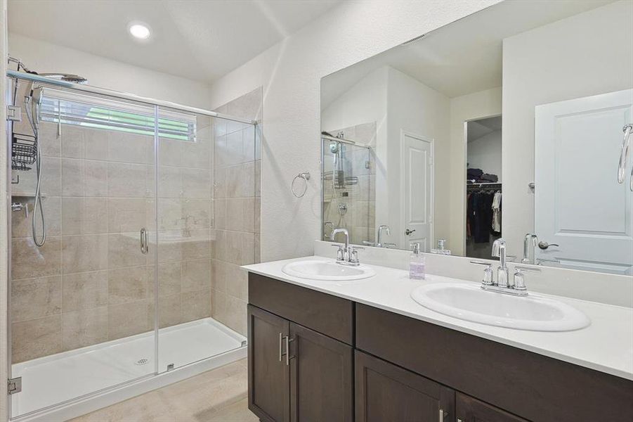 Bathroom featuring a shower with shower door and double sink vanity