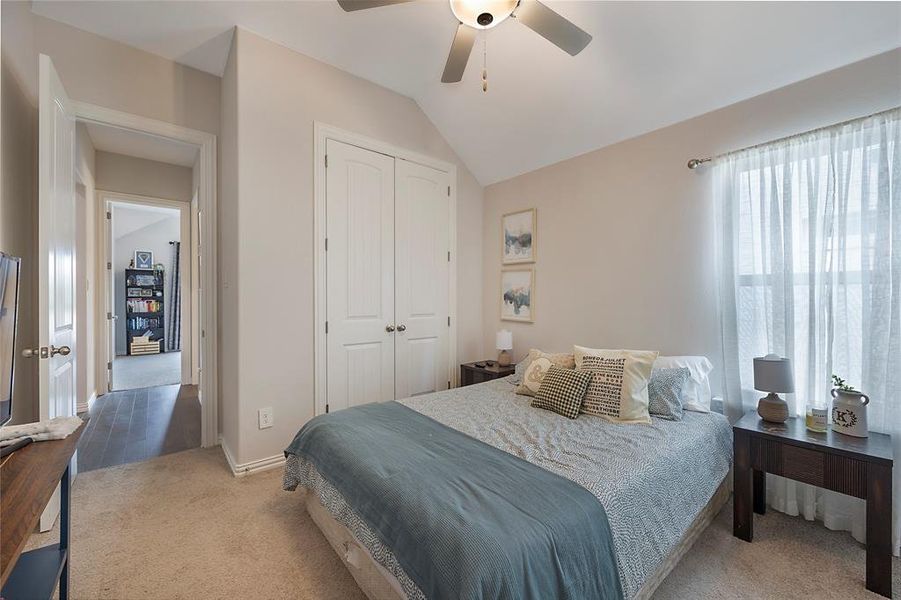 Carpeted bedroom featuring a closet, lofted ceiling, and ceiling fan