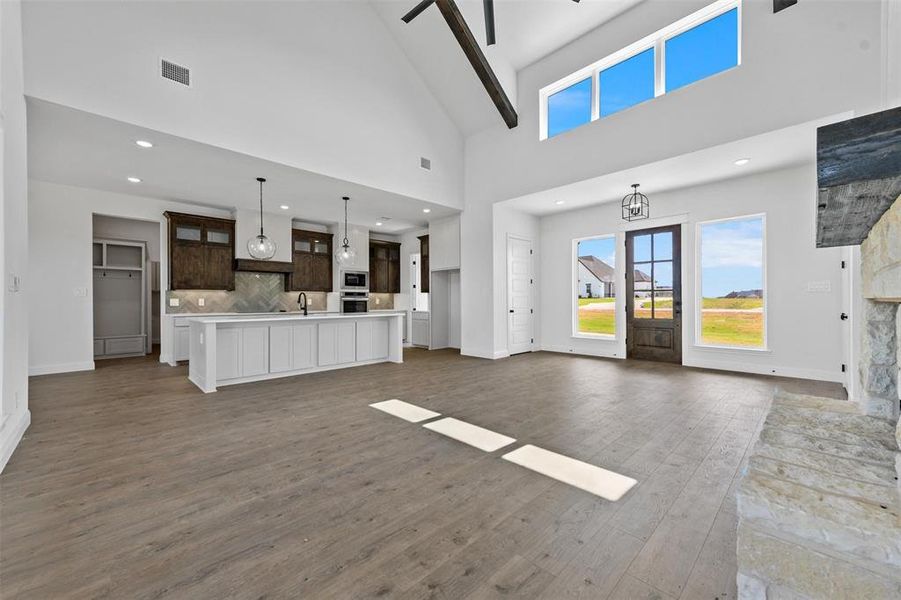 Unfurnished living room featuring high vaulted ceiling, sink, and dark hardwood / wood-style floors