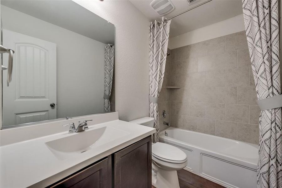 Full bathroom with shower / bath combo with shower curtain, hardwood / wood-style floors, vanity, and toilet