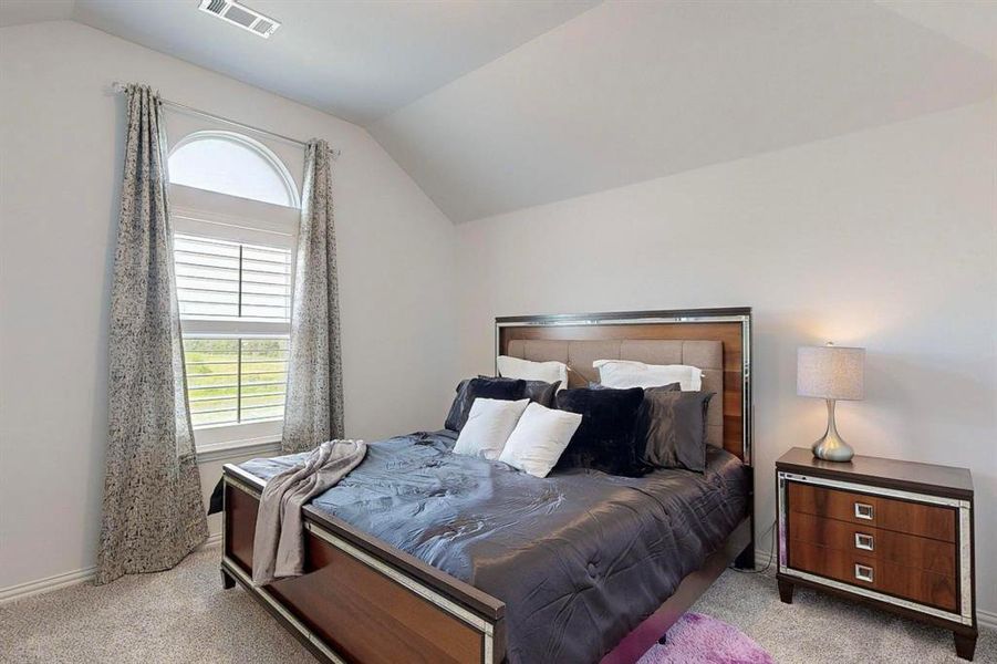 Bedroom featuring lofted ceiling and light colored carpet