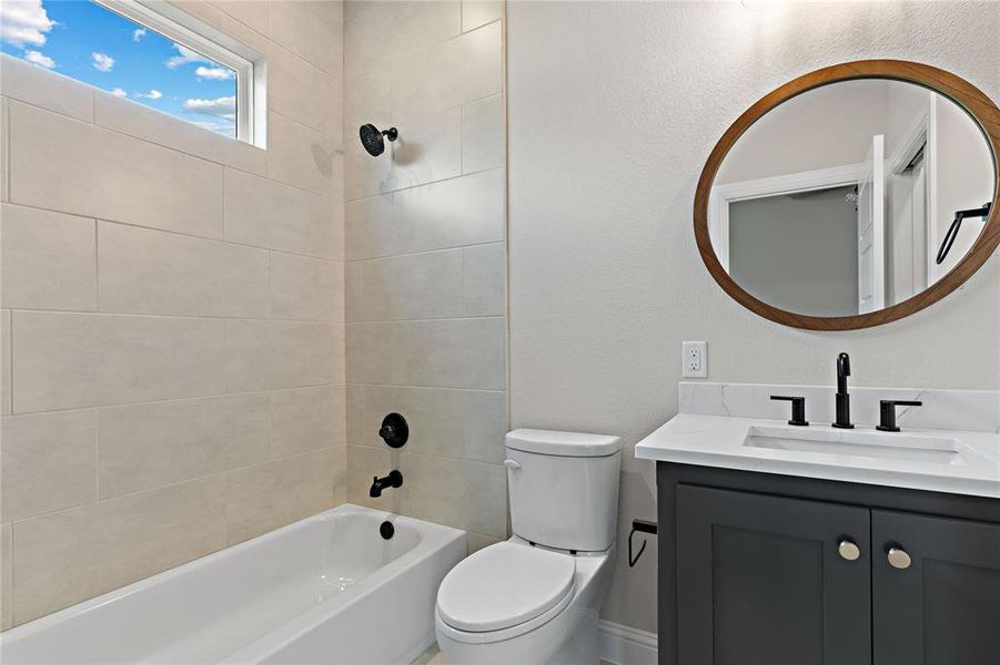 Full bathroom with tiled shower / bath, vanity, and toilet