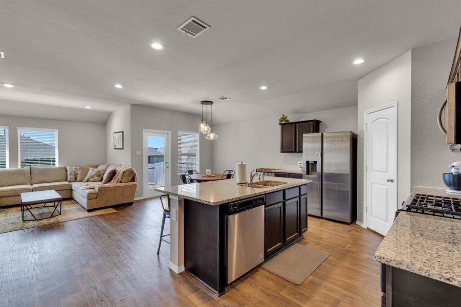 Open kitchen seamlessly flows into the living room and breakfast nook, creating a perfect space for entertaining. The kitchen features a granite countertop island with a double sink and built-in dishwasher, offering both functionality and style.