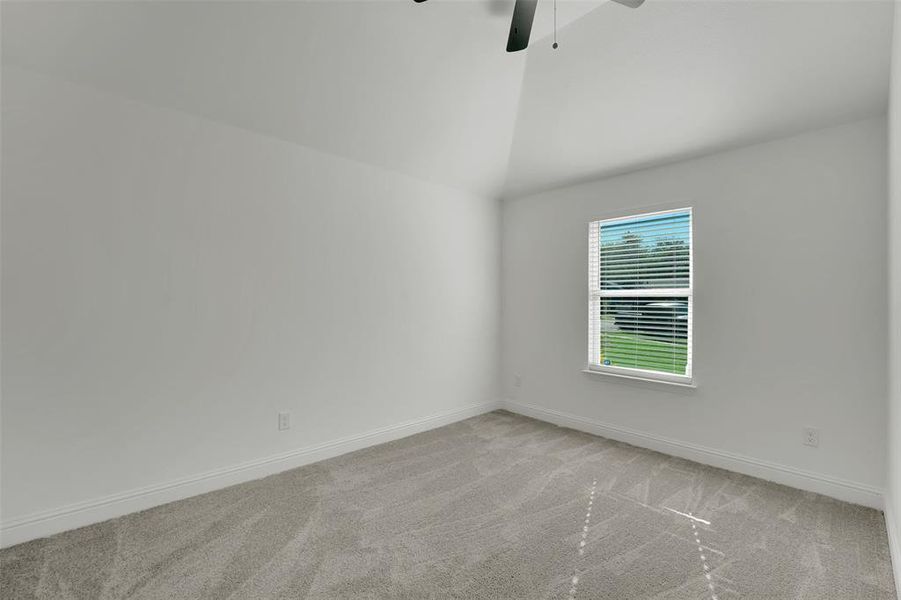 Carpeted empty room with lofted ceiling and ceiling fan