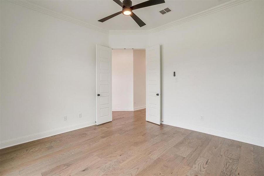 Unfurnished room with ornamental molding, light wood-type flooring, and ceiling fan